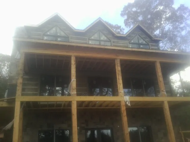 Dormers and porch framing on a large log home under construction — Roof Coating work by our crew in Burton