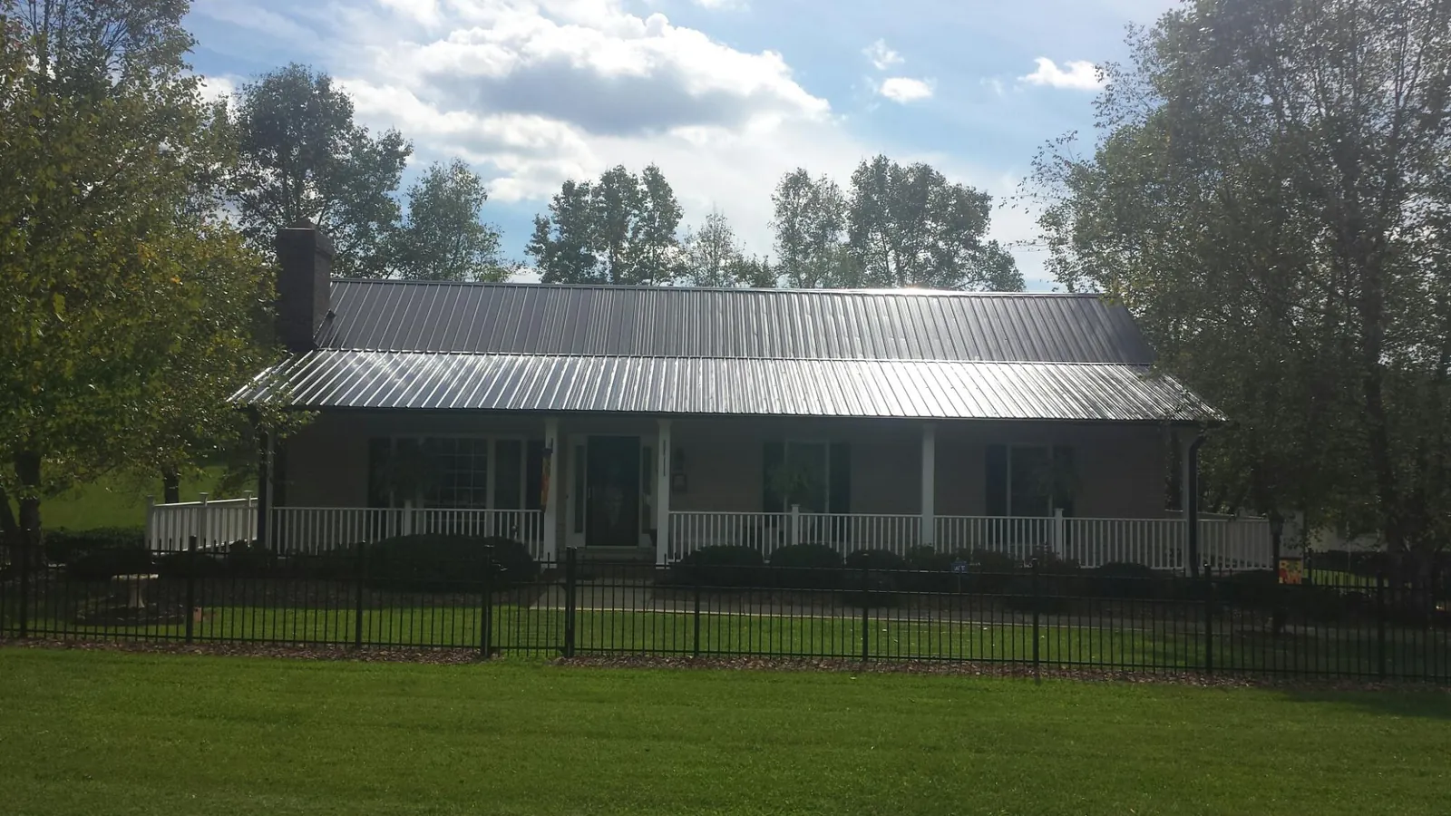 Gray metal roof on a brick ranch with a full width front porch — Gutter Guard Installation work by our crew in Burton
